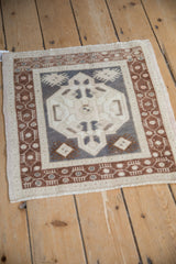 Angled view of a distressed Oushak rug showing its medallion design in ivory, silver, and copper tones.