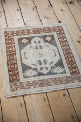 Angled view of a vintage Turkish mat with a center medallion and copper-toned border.