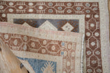 Folded corner of a vintage Oushak rug revealing the hand-knotted foundation and distressed pile.