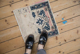 Small distressed Oushak rug mat with navy details, shown for scale next to loafers.