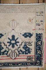 Corner of a distressed Turkish Oushak rug showing navy blue floral motifs and low, even wear.