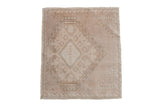 A vintage distressed Oushak square rug with a geometric gul medallion in neutral beige and ivory tones.