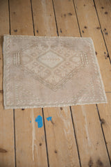 Angled view of a distressed Oushak mat highlighting its even wear and muted geometric medallion.