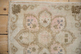 Distressed beige Oushak rug pile with machine-bound edge and subtle dusty rose patterns.