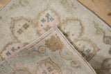Distressed vintage Oushak rug in muted ivory, blush, and sage with machine-bound edge.