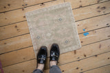 A distressed vintage Oushak mat in pale sage and ivory, shown for scale underfoot.