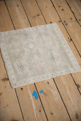 The soft, distressed texture of a vintage square Oushak rug seen from a high, angled view.