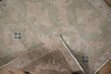 Folded corner of a distressed Oushak mat revealing the low pile and hand-knotted foundation.