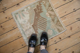 Worn geometric pattern of a distressed Oushak rug in pale green, dusty bronze, ivory.