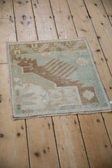 Distressed vintage Oushak rug corner, showing pale green geometric shrimp detail and fringe.