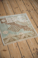 Distressed Oushak rug corner with pale seafoam green and bronze finned motifs, even wear.