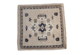 Vintage distressed square Oushak rug with a central navy medallion and wave border on an ivory field.