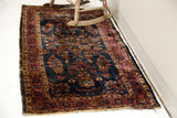 Worn rosy red border and deep blue field of a vintage Sarouk rug.