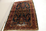 Significant wear and tear on deep blue vintage Sarouk rug with rosy red border.