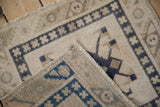 A folded corner of a distressed Oushak rug reveals its hand-knotted weave and foundation.