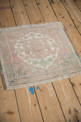A vintage Oushak rug from an angle, highlighting its distressed texture and pastel tones.