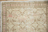 Worn, low-pile texture of a distressed Kayseri rug showing pink floral and brown border motifs.