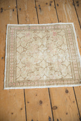 Angled view of a vintage Kayseri mat, highlighting its worn texture and pale pink blossoms on a sand field.