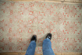 Faded blush quatrefoil floral pattern on a distressed beige Oushak rug.