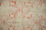 Distressed pile of a vintage Oushak rug, highlighting faded raspberry red floral and leaf motifs.