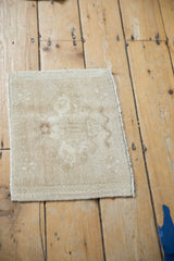 The time-softened texture and faded pattern of a square vintage Oushak rug mat.