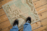 A perspective view showing the scale and worn texture of a vintage square Oushak rug.