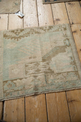 Soft, even wear on a vintage Oushak mat with a geometric design in muted green and ivory.
