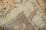 The hand-knotted back and machine-bound side of a distressed vintage Oushak rug.
