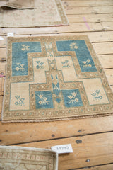 Textured pile of a distressed Oushak rug with geometric plant motifs in dusty blue and ivory.