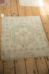 Corner of vintage Oushak rug showcasing distressed texture and geometric mint green motifs.
