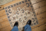 Distressed Oushak square rug mat with a blue and beige medallion, shown for scale.