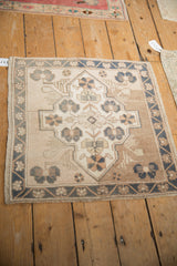 Overhead view of a distressed vintage Oushak mat with a central shield medallion in neutral tones.
