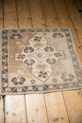 An angled perspective of a distressed Oushak rug's shield medallion and dusty blue border.