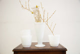 White hobnail milk glass trumpet vase, filled with dried branches and yellow flowers.