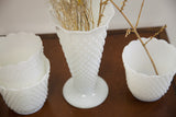 White hobnail milk glass vases in trumpet and planter styles, holding dried stems.
