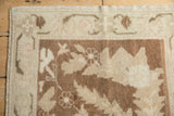 Corner detail of a distressed Oushak rug showing its low pile and intact side cord edge.