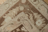 Folded corner of a vintage Oushak rug revealing its hand-knotted foundation and intact side cord.