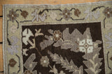 Close-up of the distressed Oushak pile showing knot heads and mauve serrated leaf patterns.