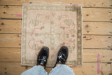 Distressed vintage Oushak rug corner, dusty rose and sea foam green motifs, consistent wear.