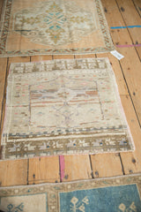 Vintage Oushak mat showing even wear across the knot heads and a faded geometric design.