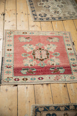 Distressed blush pink Oushak rug's lower section with cherry red band and subtle palmette motifs.