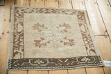 Angled overhead view of a distressed Oushak mat showing the low pile and soft, earthy palette.
