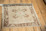 Angled view of a distressed Oushak mat showing color variation across its floral medallion.