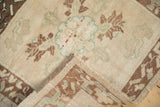 Folded corner of a vintage Oushak rug showing its hand-knotted back and secured side cord.
