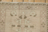 Upper corner of distressed Oushak rug, displaying faded floral motifs and coffee brown wave border.