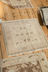 Detail of distressed Oushak rug, showing even wear on muted ivory floral field and wave border.