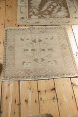 Corner detail of distressed Oushak rug, showing reciprocating wave border and simplistic floral motifs.