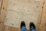 Soft, worn pile of a vintage distressed Oushak rug with faded cream and sea foam floral motifs.