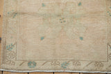 Distressed Oushak rug corner, showing even pile wear, cream, and turquoise floral motifs.