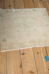Distressed cream Oushak rug corner showcasing mostly even wear and subtle turquoise blossoms.